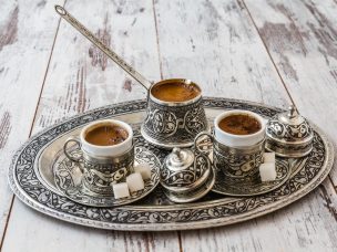 Traditional Turkish coffee in traditional silver cup with silver pot and tray