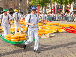 ALKMAAR, THE NETHERLANDS - SEPTEMBER 7: Carriers walking with many cheeses in the famous Dutch cheese market, September 7, 2012 in Alkmaar, The Netherlands. The event happens in the Waagplein square.