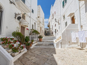 Picturesque narrow street with traditional white washed houses in the old historic center in Ostuni, Puglia, Italy.
