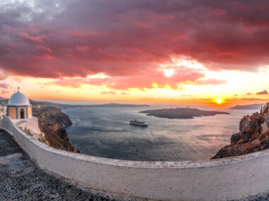 Old Town Thira on the Santorini island, famous churches against caldera with sunset over sea in Greece.