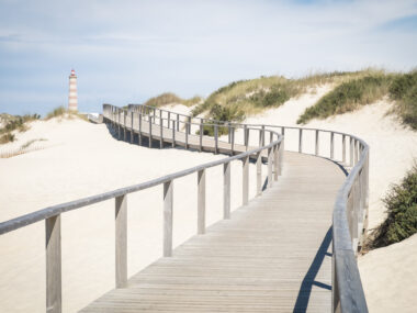 Symbol of city Barra, Praia da Barra Portuguese lighthouse on coast, wooden pier at beach