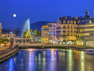 Urban view with famous fountain by night with full moon, Geneva, Switzerland, HDR